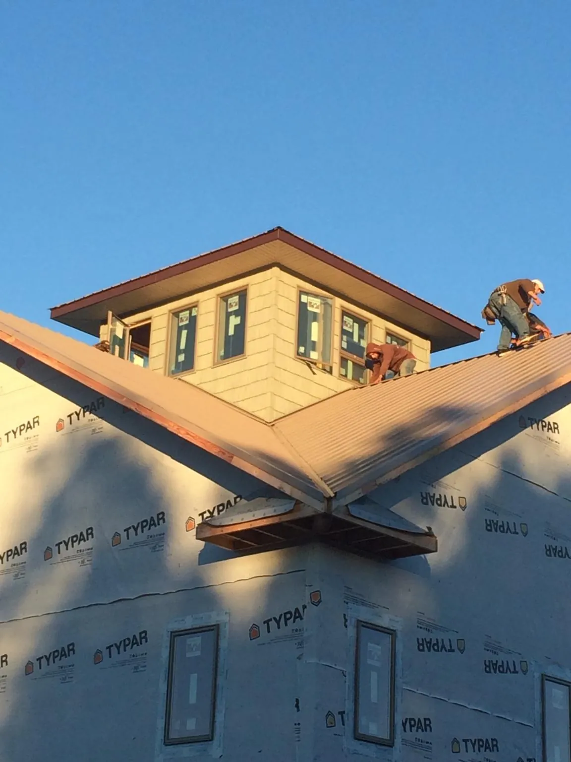 Roofers working around a rooftop cupola on a new metal roof at sunset — Roof Waterproofing in Ripley by Roofing Brothers